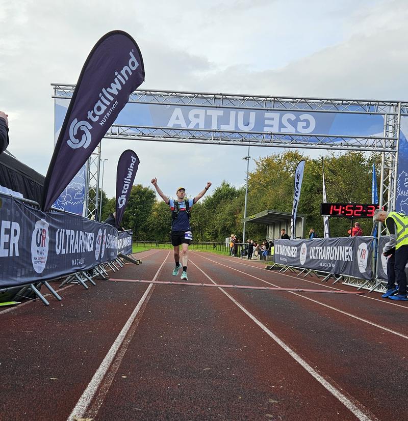 Me running across the finish line with arms stretched in the air. Credit: Derek Marshall